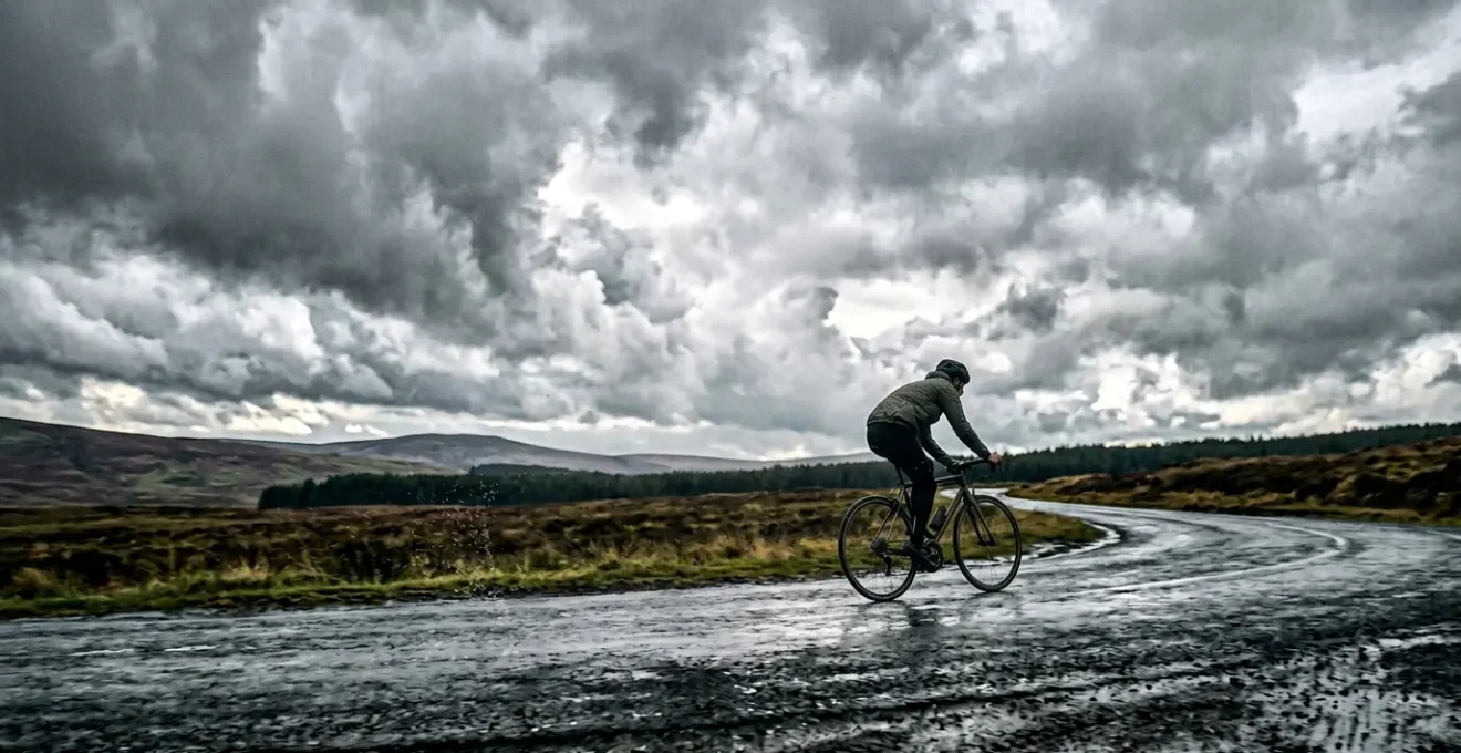 Radfahrer in Regenjacke bei wechselhaftem Wetter auf dem Weg