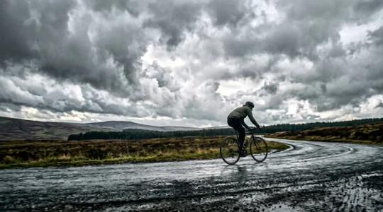 Radfahrer in Regenjacke bei wechselhaftem Wetter auf dem Weg