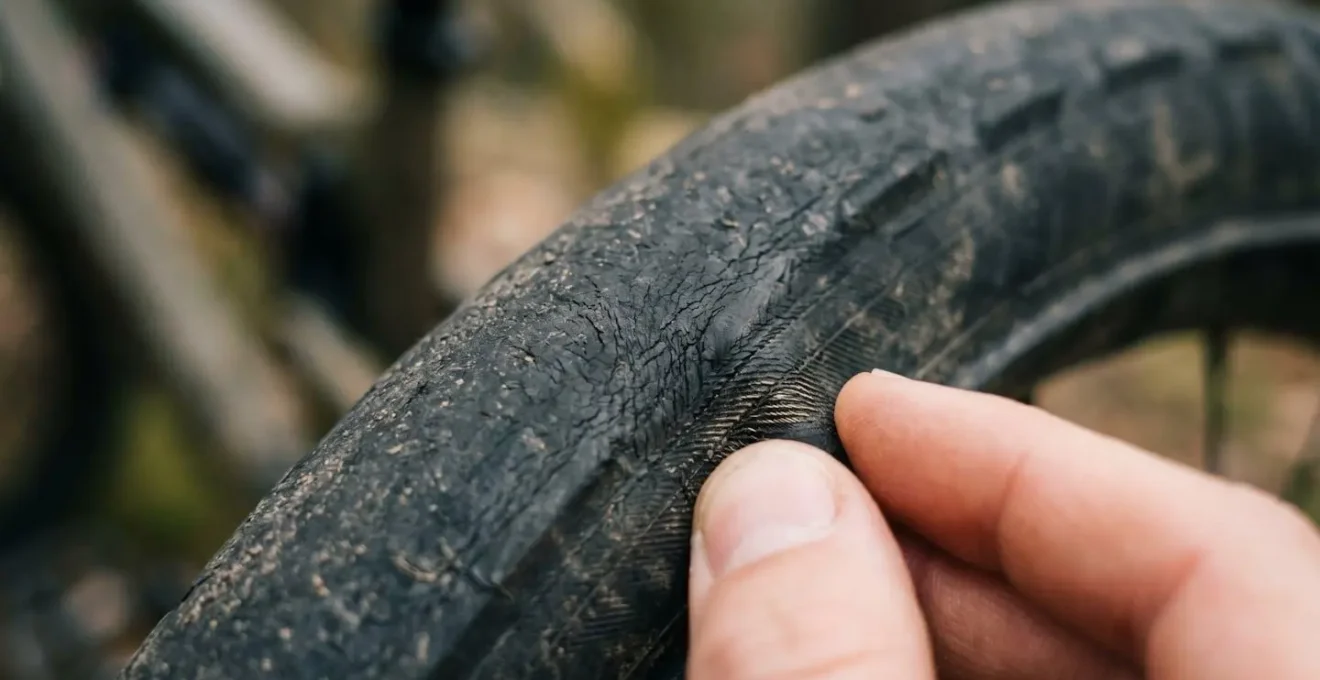 Nahaufnahme einer Mountainbike-Reifenseitenwand mit Fingern, die einen Riss ertasten
