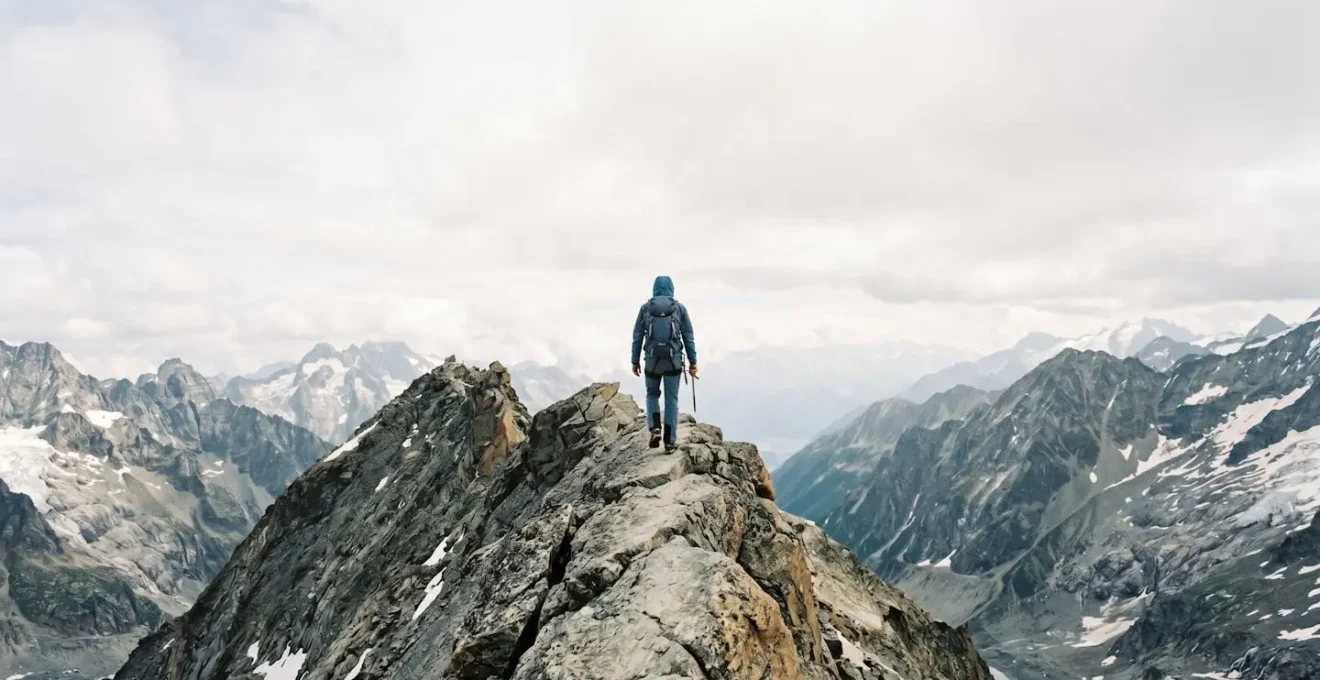 Wanderer auf schmalem Berggrat demonstriert Fokus und Angstbewältigung in exponierter Situation.