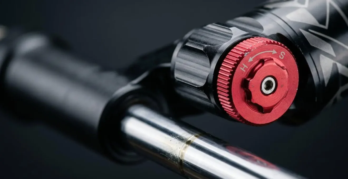 Nahaufnahme eines roten Zugstufenrädchens an einem Mountainbike-Dämpfer mit sichtbarem Verstellmechanismus